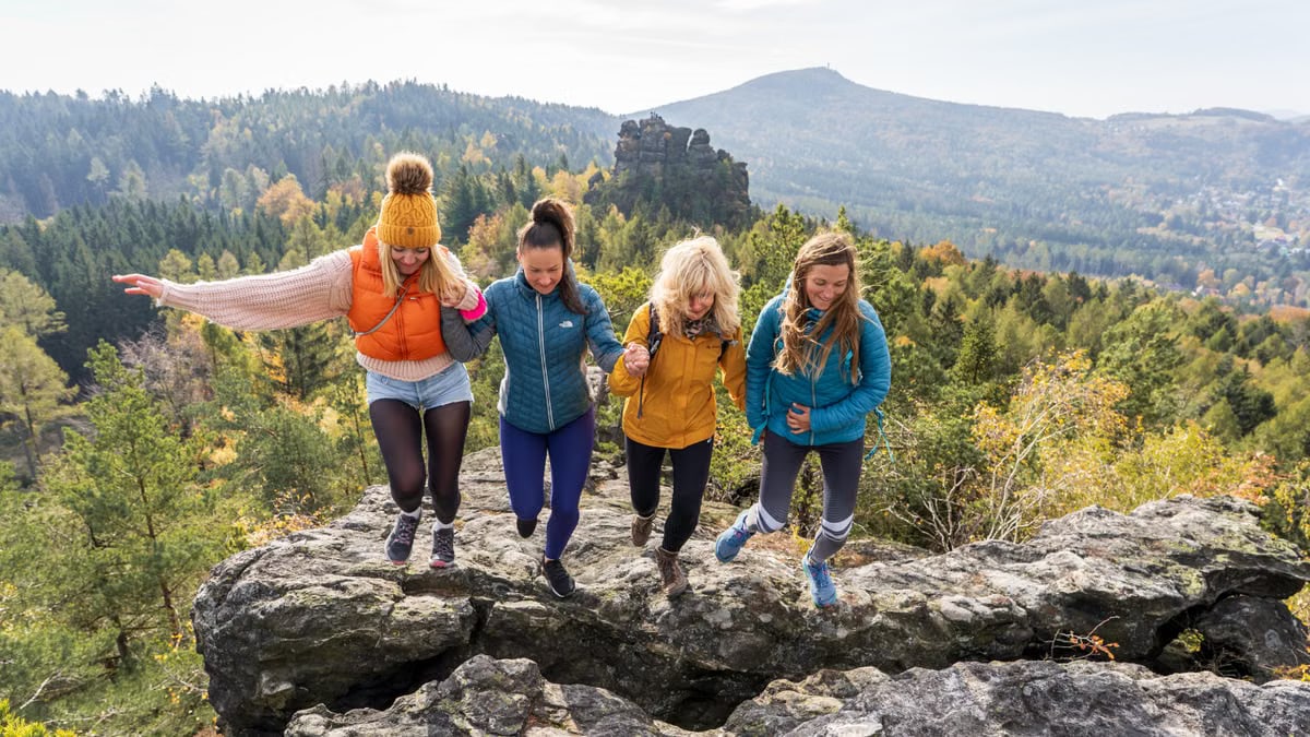Four friends enjoying a joyful hike on Oybin's rocky terrain with scenic views.